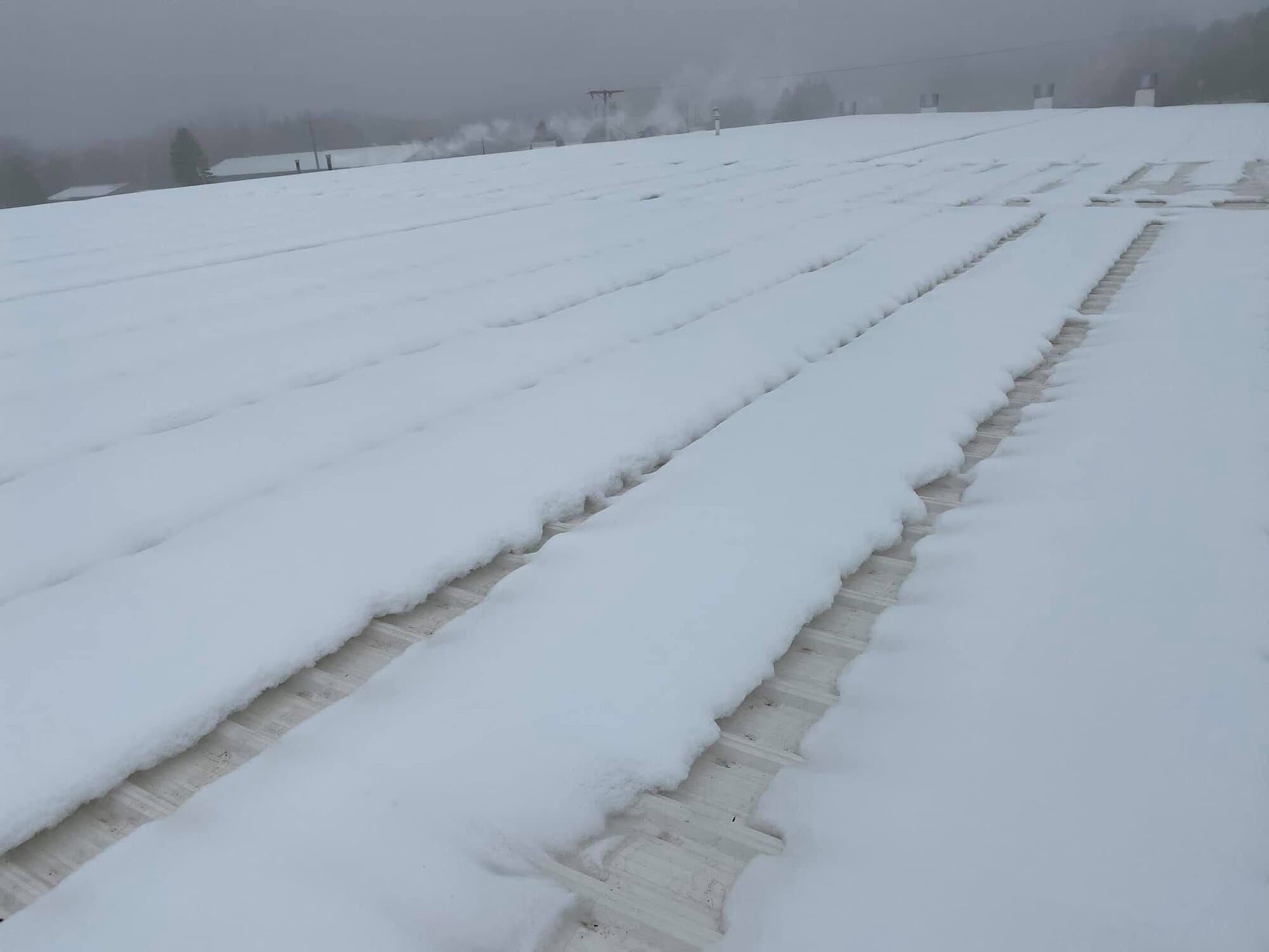 Snow is melted in strips on top of the roof where heat is escaping